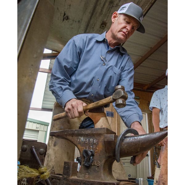 Farrier Blane Chapman shapes a shoe at the anvil.