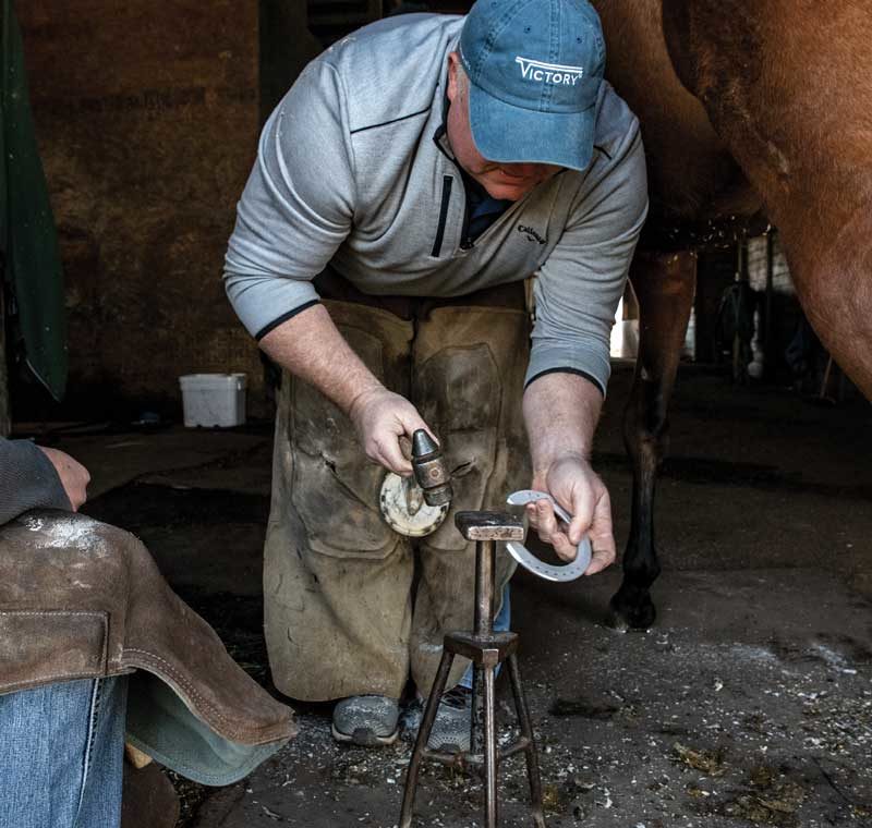 Farrier Pat Broadus shaping a shoe at a stall jack.